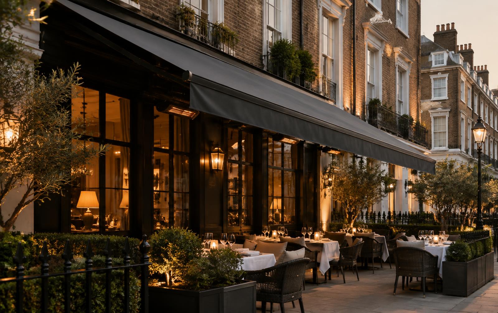 Restaurant terrace in London with a charcoal retractable awning over outdoor dining tables at dusk